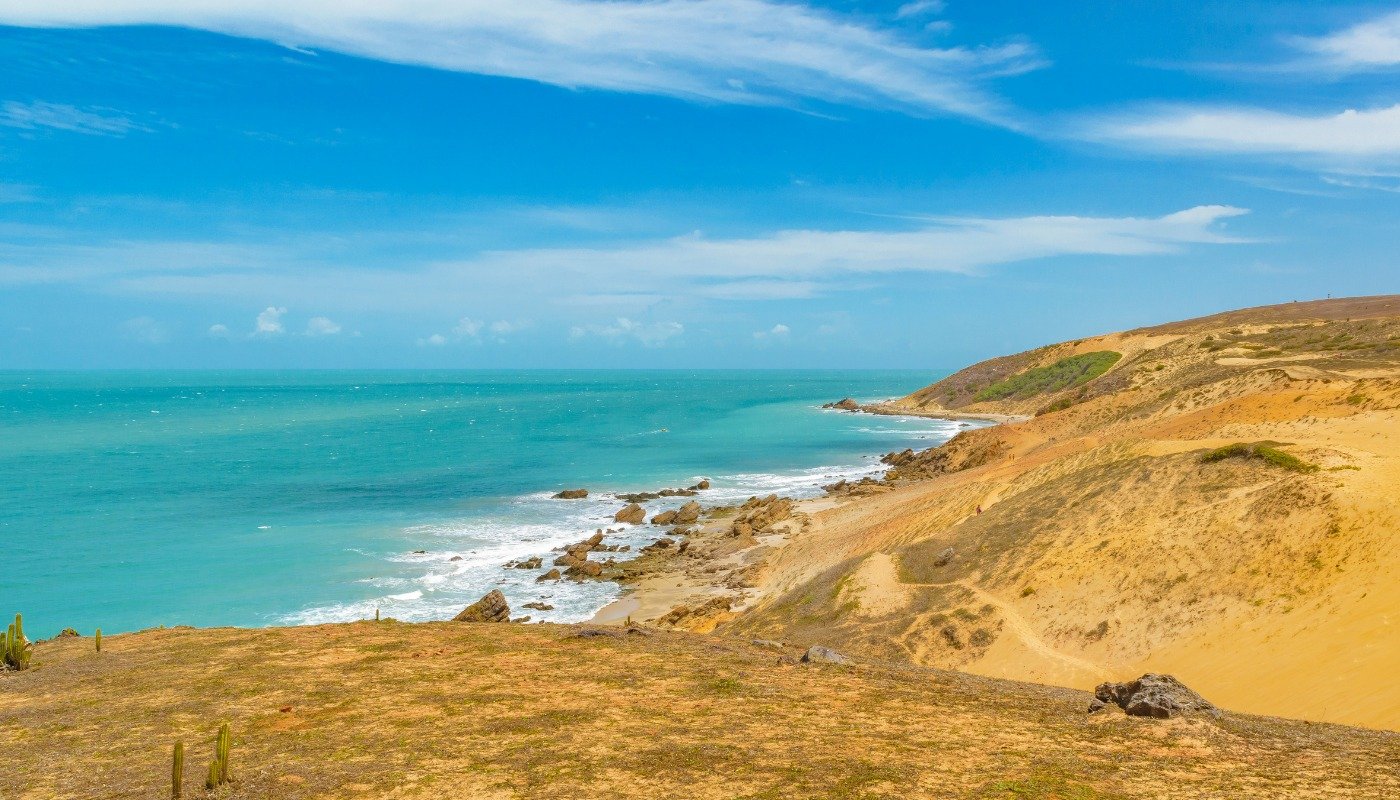 Vista panorâmica das dunas e do litoral de Jericoacoara, com mar azul e extensa faixa de areia