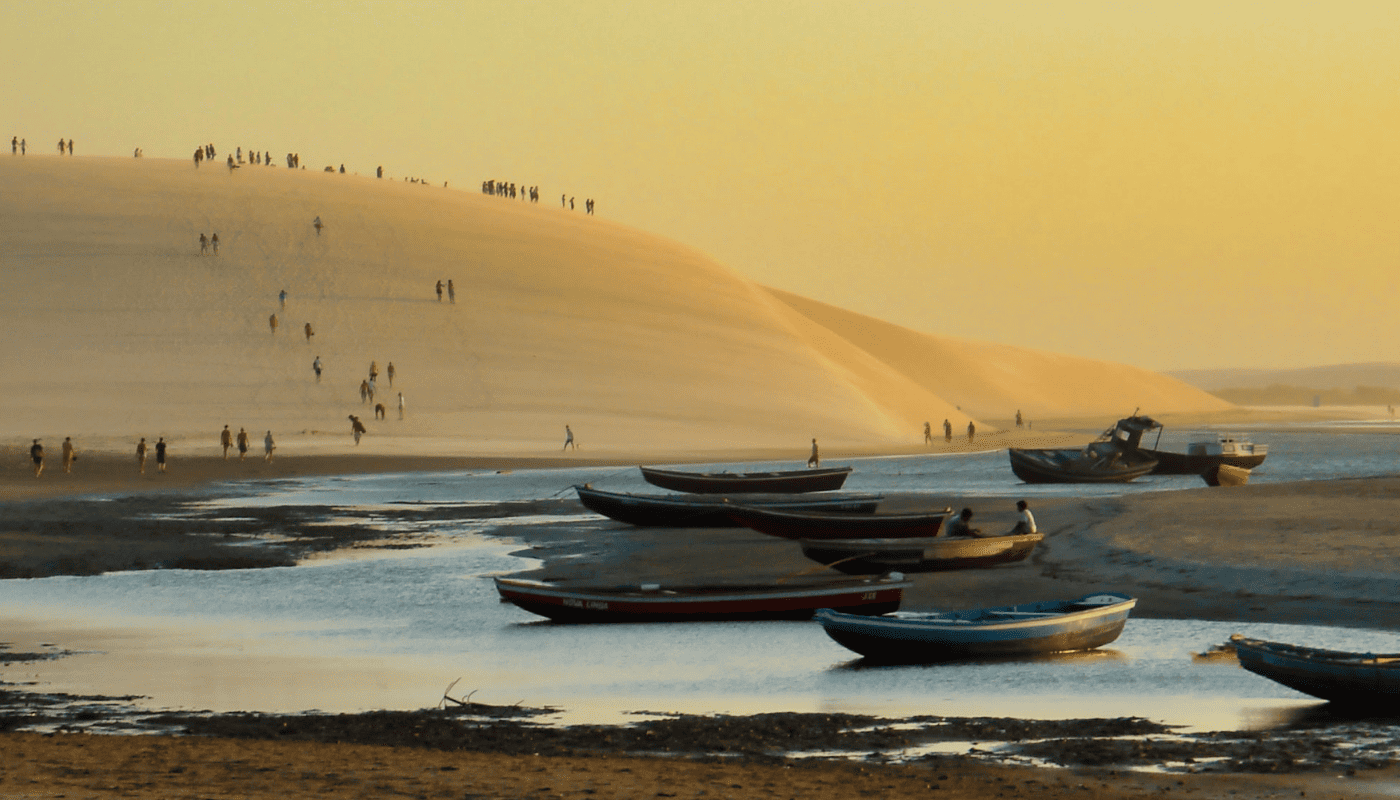 Trilha pelas dunas de areia na região de Jericoacoara, Ceará, com visitantes caminhando pela paisagem